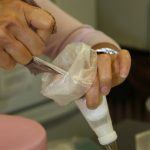 squeezing-icing-through-nylon-so-that-royal-icing-doesnt-clog-piping-tip-300x450